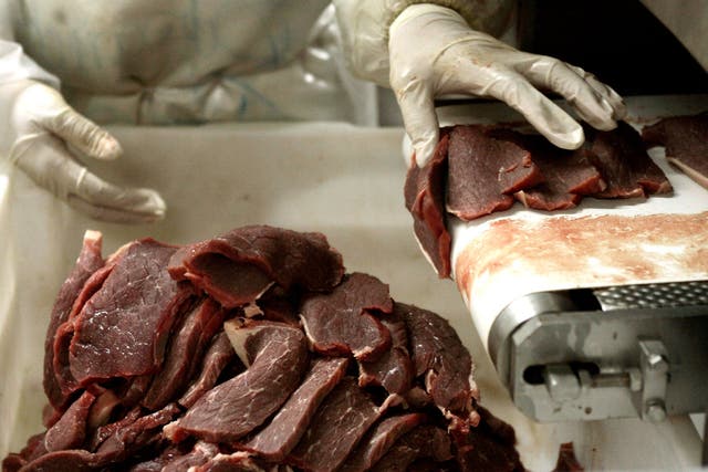 A butcher chops pieces of meat at an abattoir