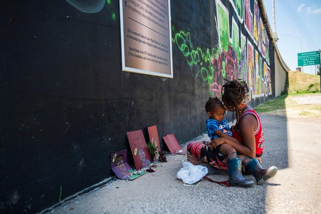 Iyammah Lunah, 28, and her son Amaru Jno Baptiste, 2, visit the Black Wall Street mural in the Greenwood district of Tulsa. Lunah said she has been visiting the wall daily leading up to the Juneteenth observance