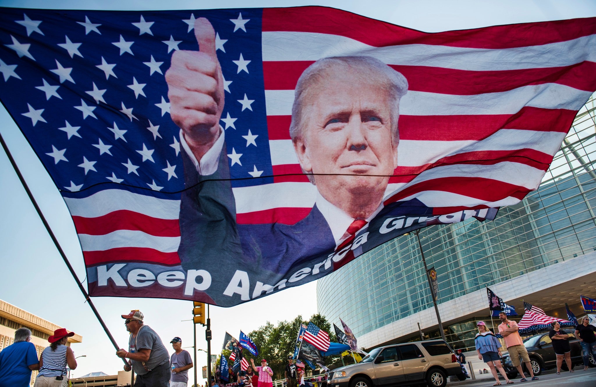 Randal Thom, of Minnesota, waves an oversized flag of President Trump outside the BOK Center in Tulsa