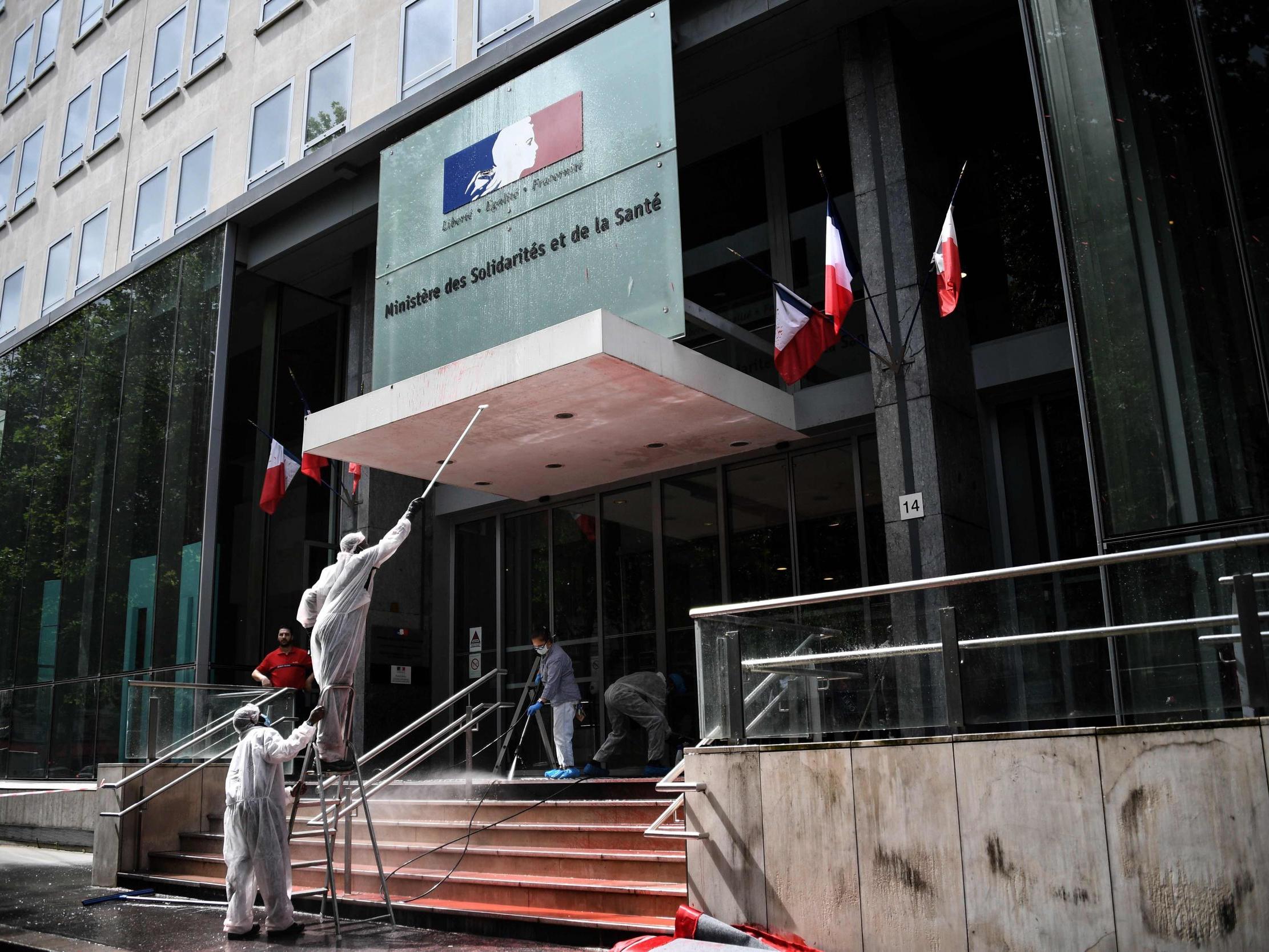 Employers clean the entrance of the French Health Ministry soiled by red paint after French activists of Attac stage a protest in support of medical workers