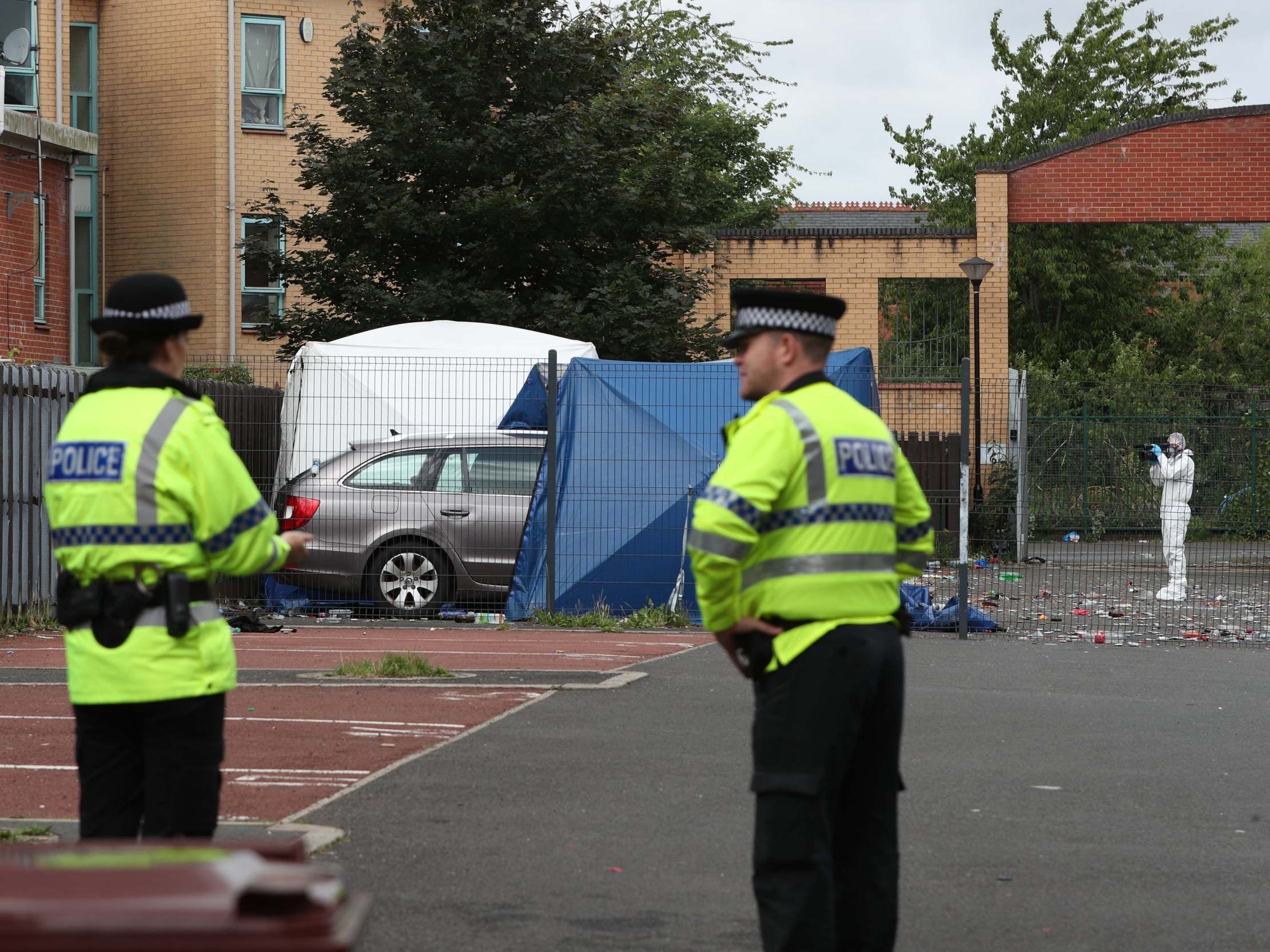 Police at the scene in a courtyard in the Moss Side area of Manchester