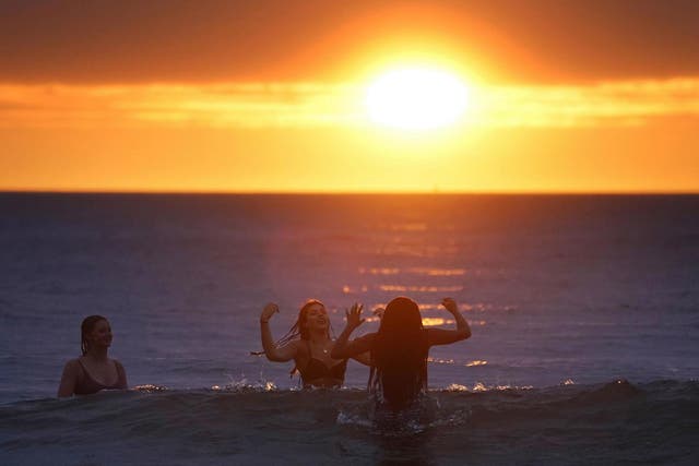 People in the water during sunrise at Tynemouth after the shortest night of the year on 21 June, 2020.