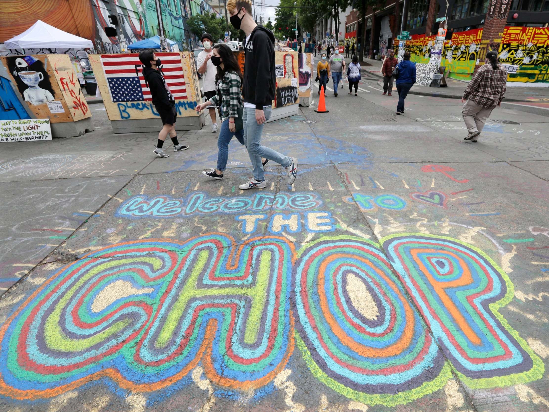 Pedestrians walk by the entrance to the Capitol Hill Occupied Protest zone in Seattle