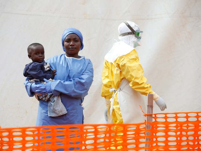 Mwamini Kahindo, an Ebola survivor, holds an infant outside the red zone at the treatment centre in Butembo, Democratic Republic of Congo