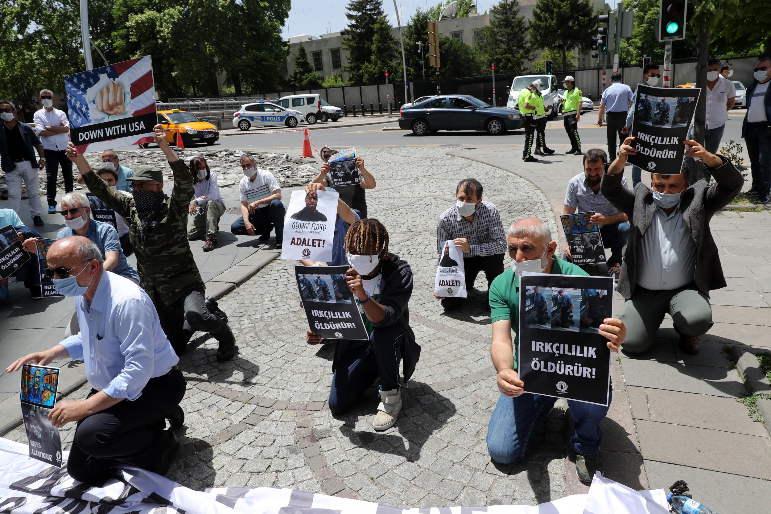 Protesters kneel and hold placards in Ankara, during a demonstration against racism and police brutality (AFP/Getty)