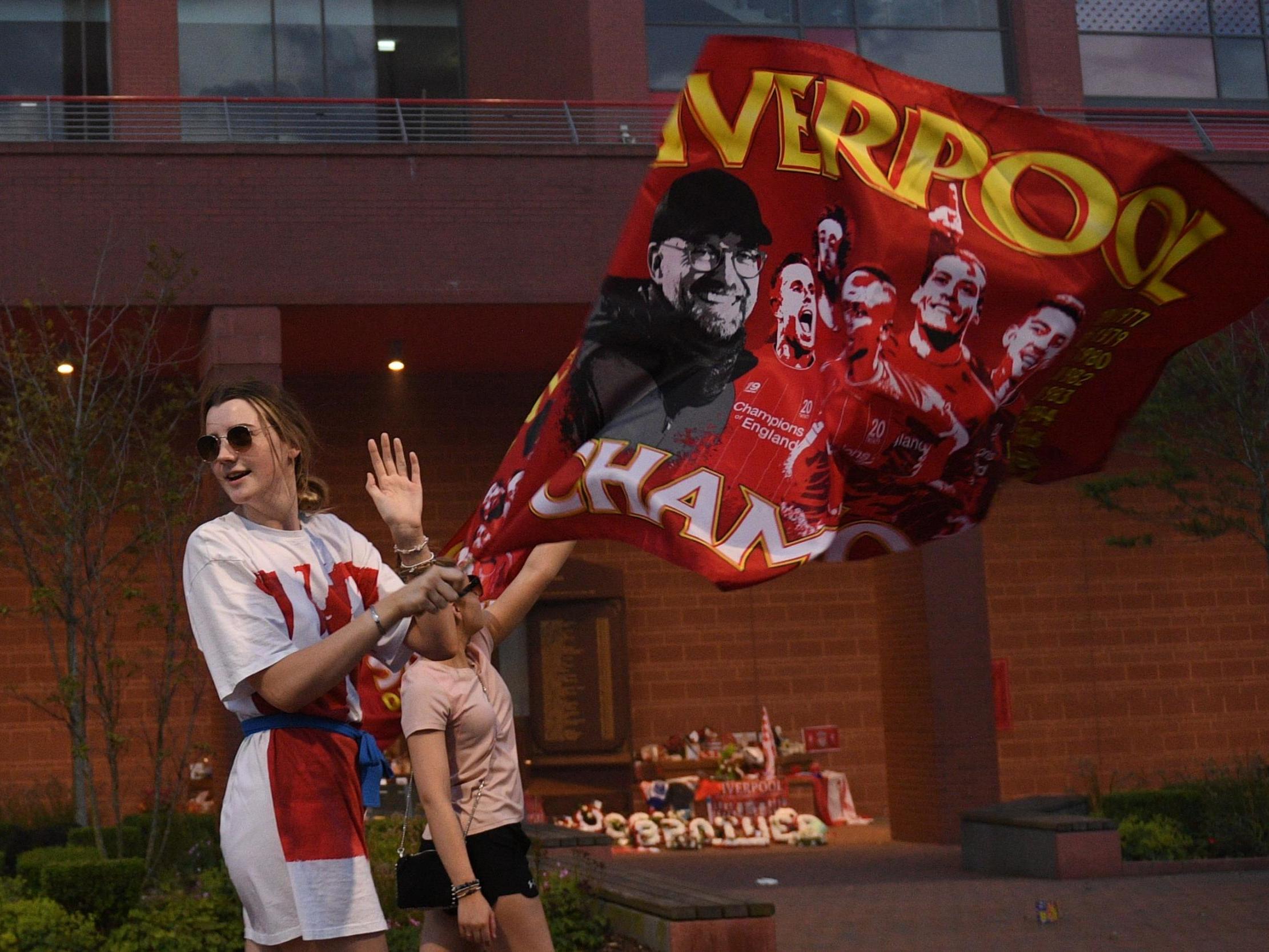Fans carry flags to celebrate Liverpool winning the Premier League title