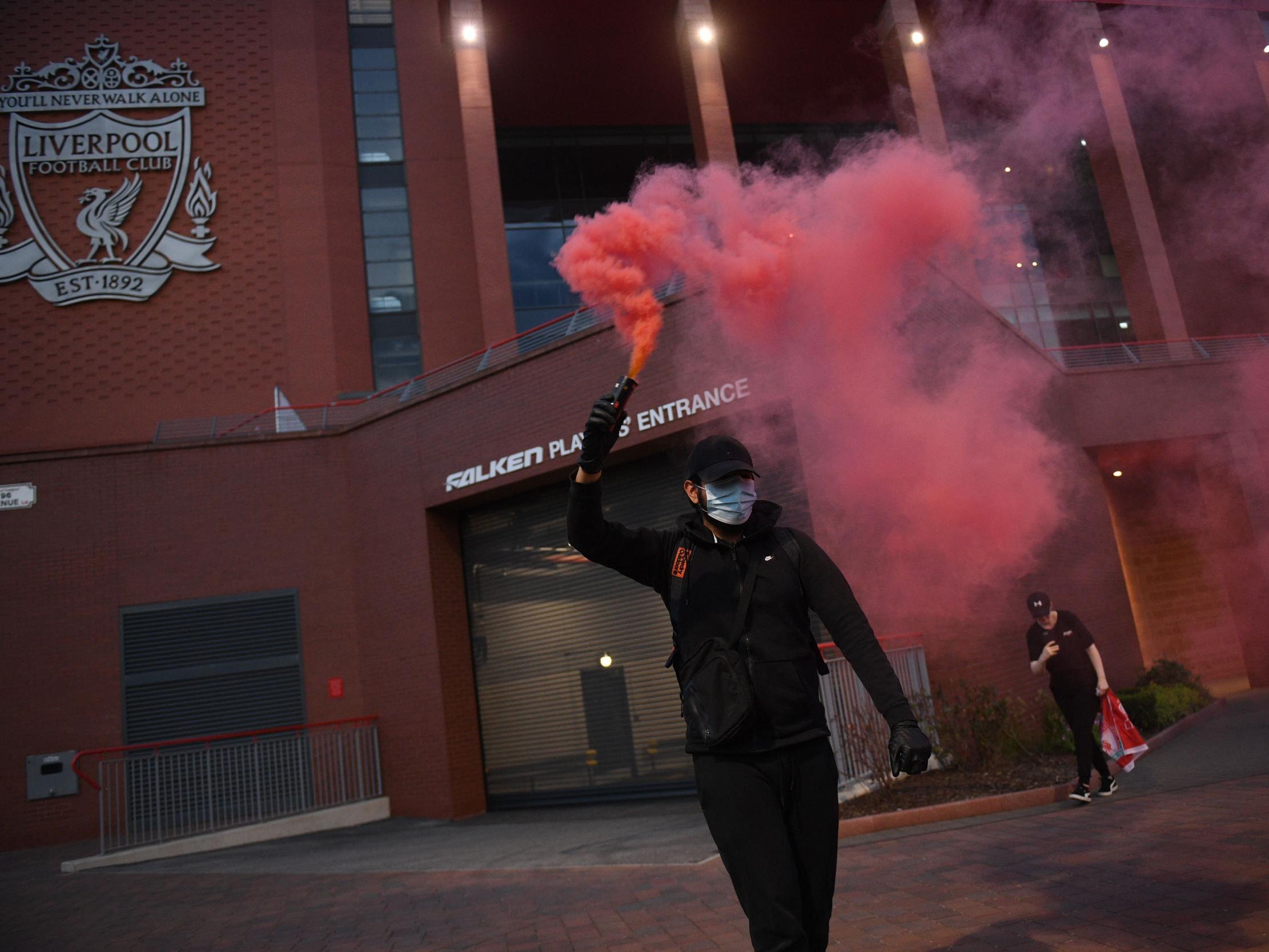 A fan carries a flare as they celebrate Liverpool winning the title