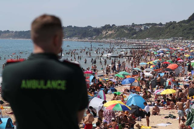 An ambulance worker looks out from Bournemouth Pier as large crowds gather on Bournemouth beach during the heatwave, 25 June 2020.