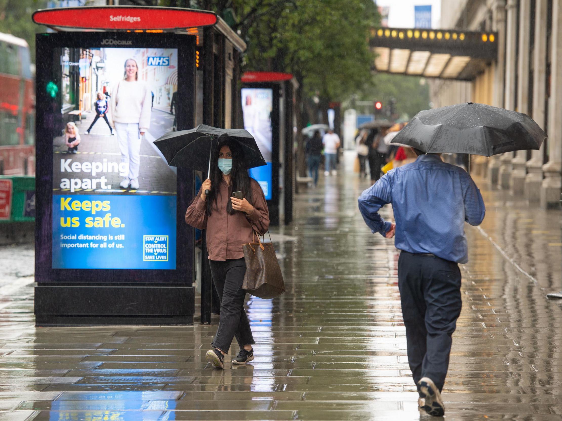 A shopper passes a social distancing sign on Oxford Street, London, as further coronavirus lockdown restrictions are lifted in England