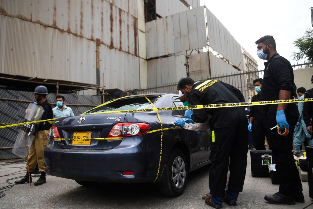 Members of Crime Scene Unit investigate a car used by alleged gunmen at entrance of Stock Exchange building