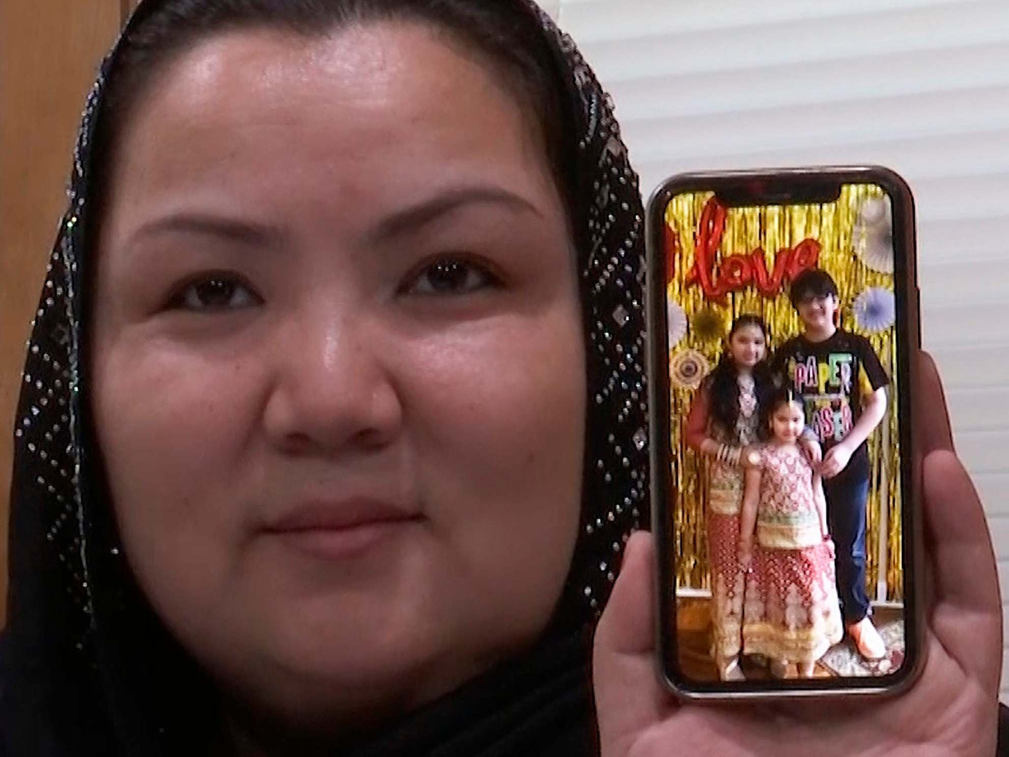 Zumret Dawut holds a phone with a picture of her kids at her home in Woodbridge