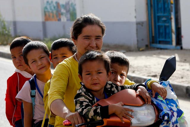 <p>Una mujer uigur y niños se sientan en un triciclo después de la escuela en Unity New Village en Hotan, en la región occidental de Xinjiang de China. Las tasas de natalidad en las regiones mayoritariamente uigures de Hotan y Kashgar se han desplomado en más del 60% desde 2015, según muestran las estadísticas del gobierno. </p>