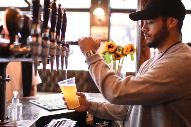 A bartender pours pints for takeaway customers at The Ten Bells pub in east London on June 27, 2020.
