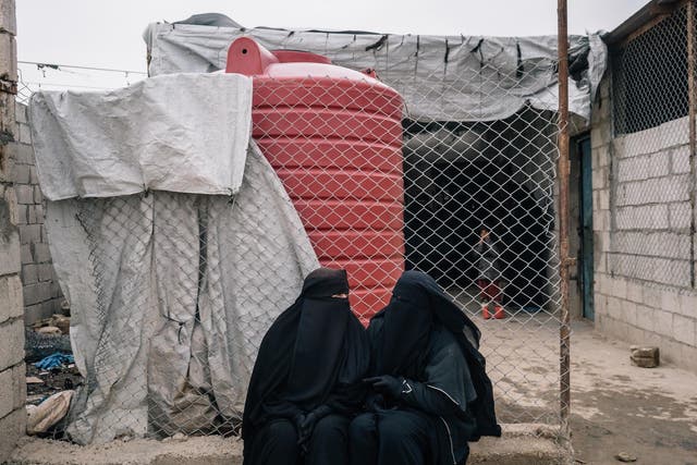 Russian women sit outside a shop in the foreigner's section of al-Hol camp in December 2019