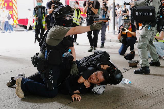 A police officer raises his pepper spray handgun as he detains a man during a march against the national security law at the anniversary of Hong Kong's handover to China from Britain in Hong Kong