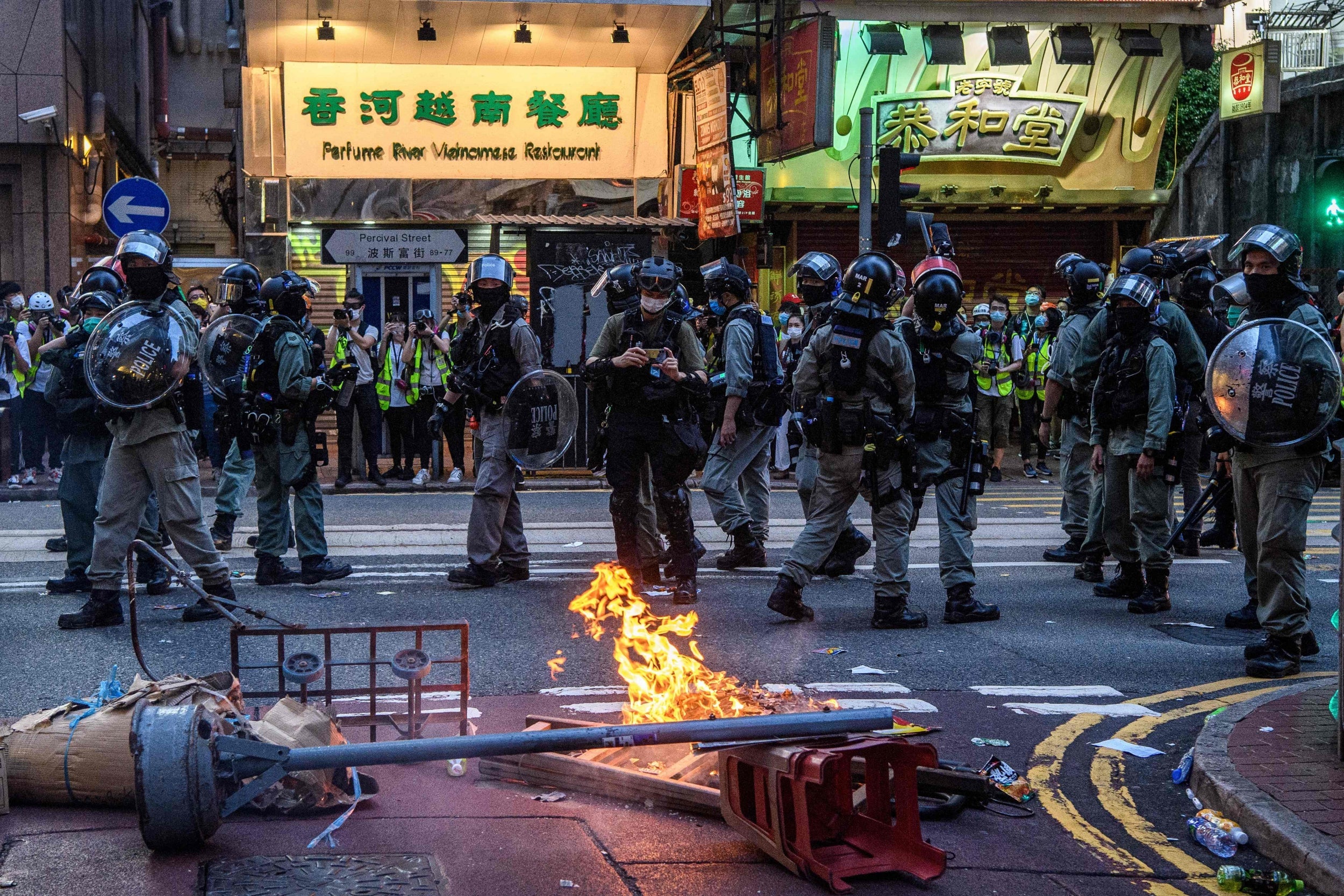 Police walk past a burning barricade set up by protesters during a rally against the law in Hong Kong on Wednesday