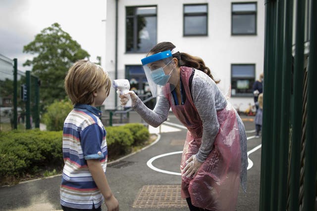 A member of staff wearing personal protective equipment (PPE) takes a child's temperature at the Harris Academy's Shortland's school