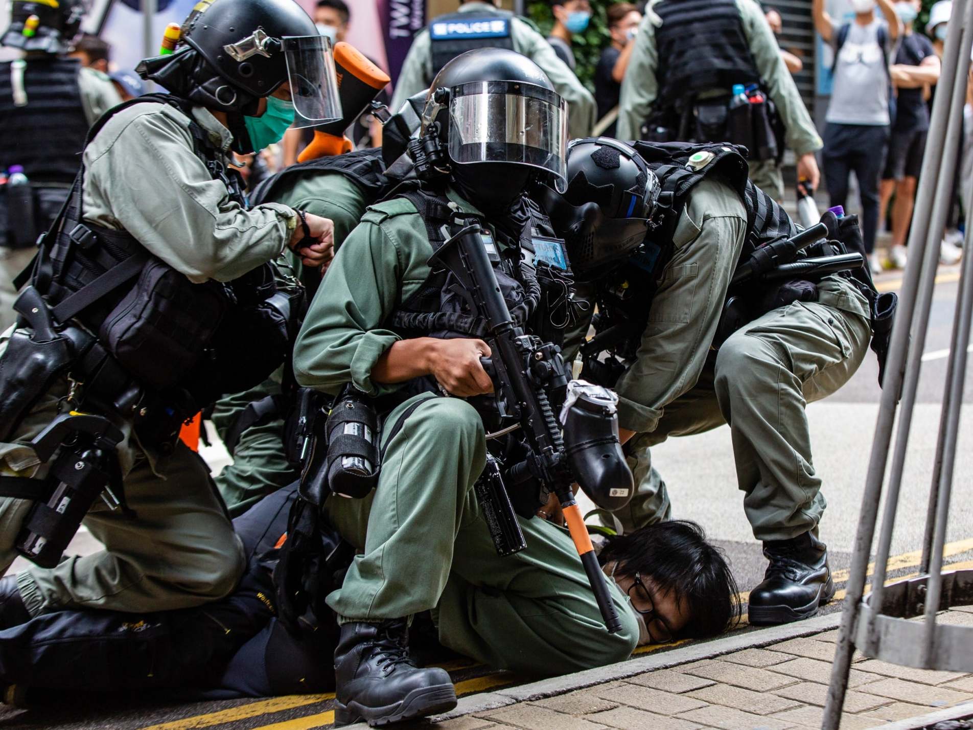 Riot police officers pin down a demonstrator in the city