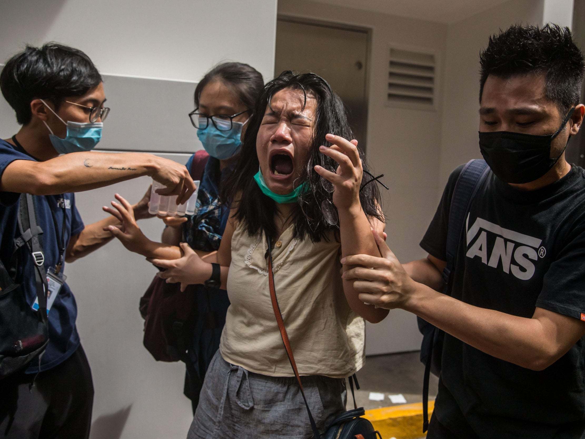 A woman reacts after she was hit with pepper spray deployed by police as they cleared a street with protesters rallying against a new national security law in Hong Kong on July 1, 2020.