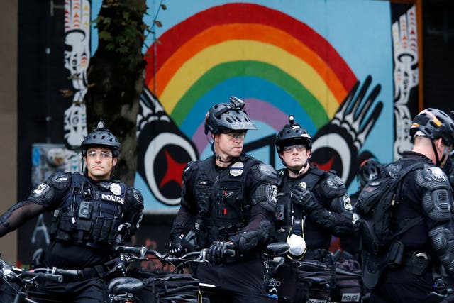Officers on bicycles stand under a rainbow mural as Seattle Police retake the Capitol Hill Occupied Protest (CHOP) area, including their East Precinct, in Seattle, Washington