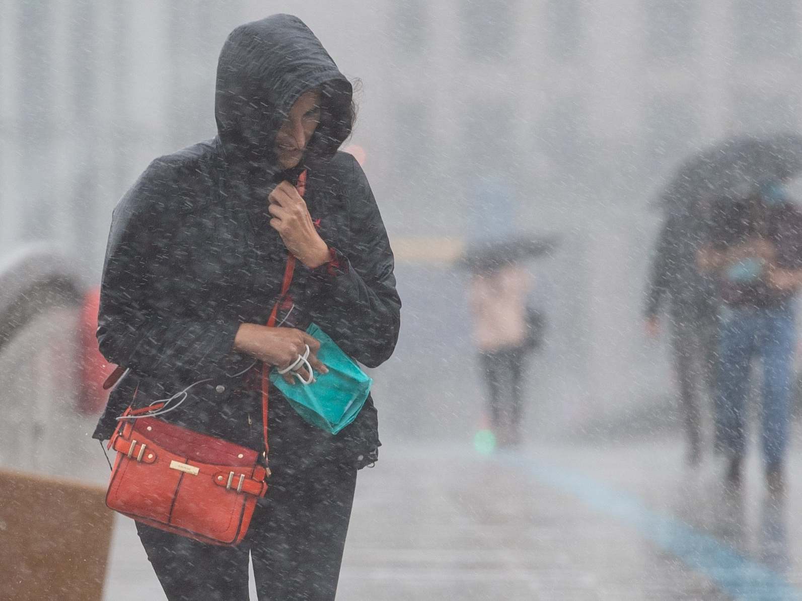 A woman runs to take shelter from a heavy downpour of rain on London Bridge, in central London
