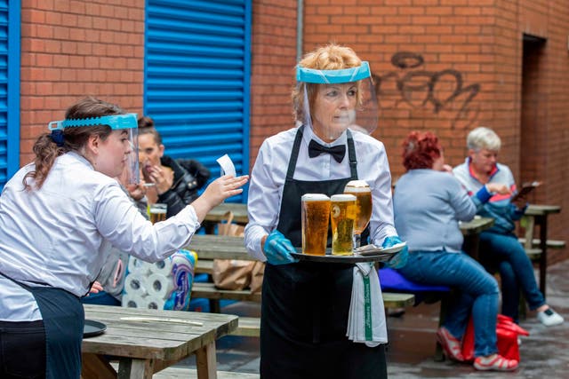 Staff wearing PPE serve people enjoying a drink in Belfast city centre on Friday