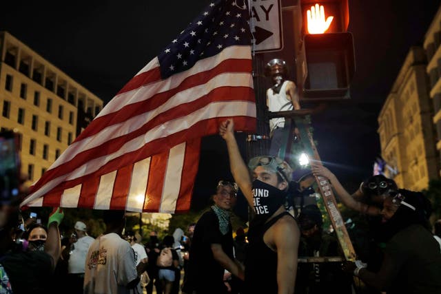 A protester holds a lighter to an American flag outside of the White House in June amid anti-racism demonstrations following the police killing of George Floyd