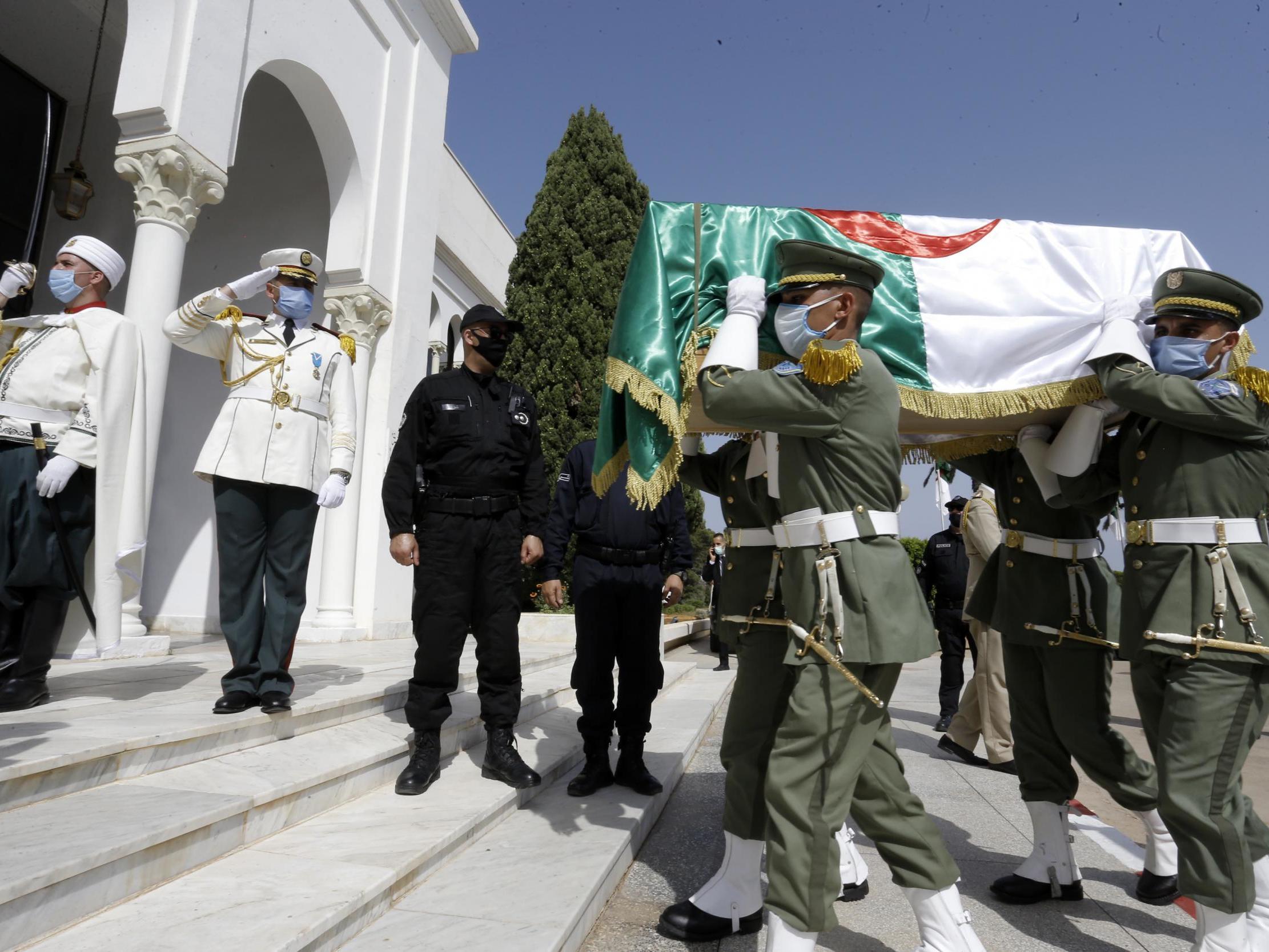 The remains of 24 Algerians are carried by members of the Algerian Republican Guard