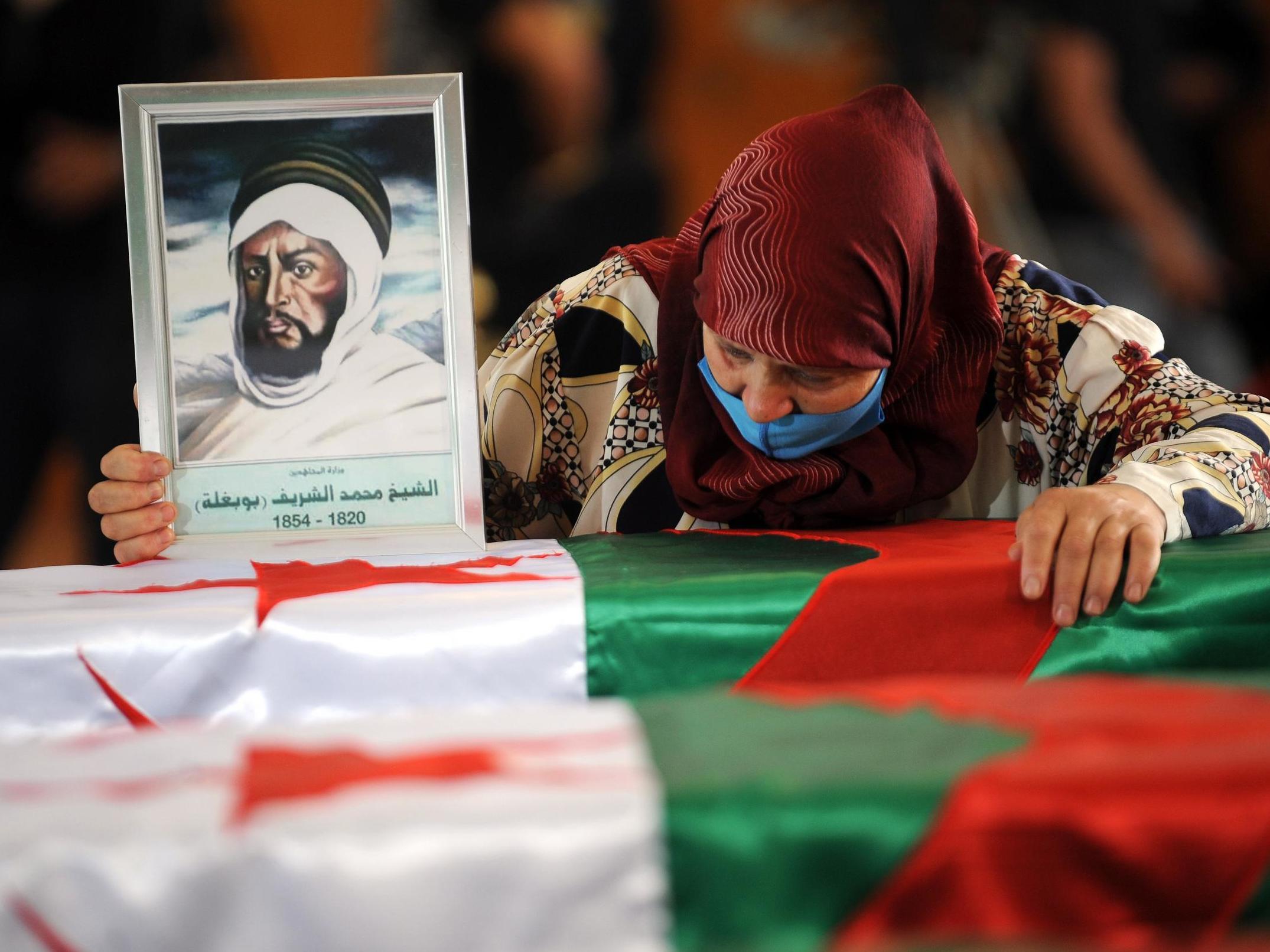 A woman mourns over one of the coffins containing the remains of 24 Algerian resistance fighters