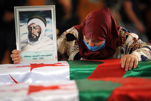 A woman mourns over one of the coffins containing the remains of 24 Algerian resistance fighters