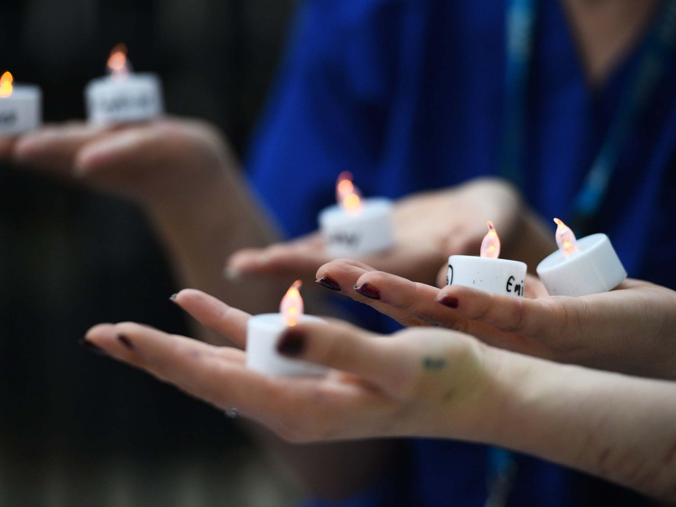 Nurses hold candles bearing the names of 235 health and social care workers that have died from coronavirus during a vigil outside Downing Street