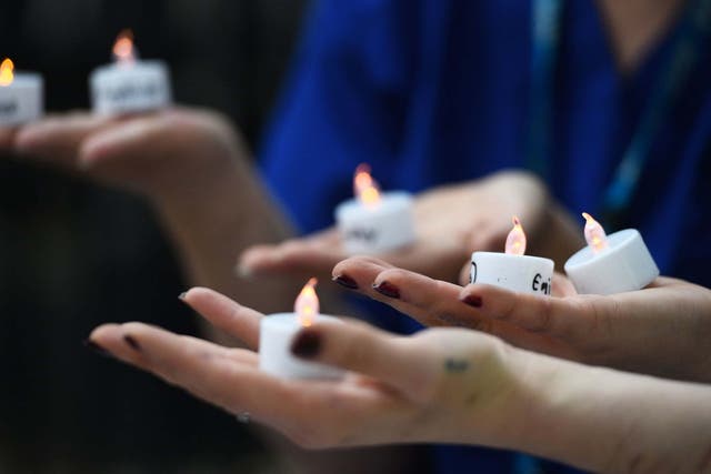 Nurses hold candles bearing the names of 235 health and social care workers that have died from coronavirus during a vigil outside Downing Street