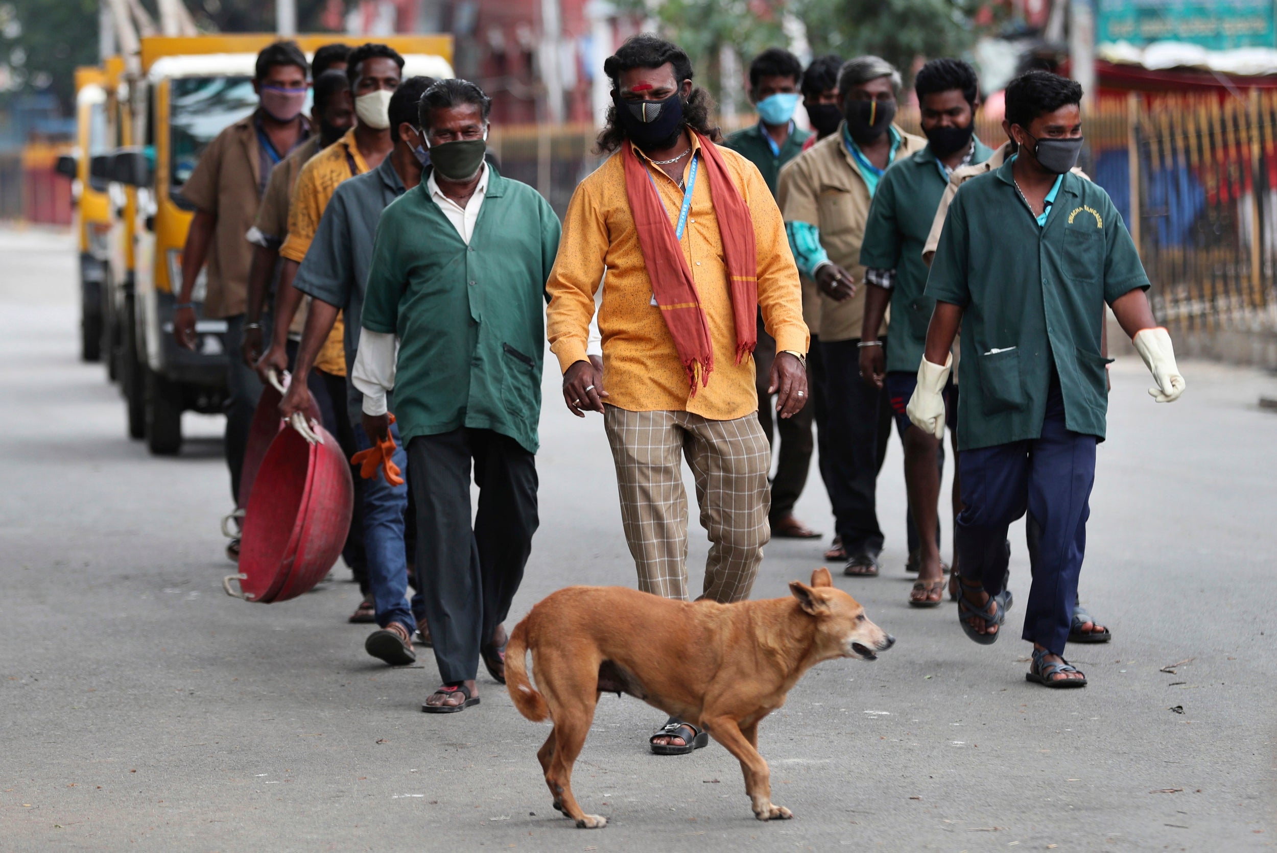 Indian municipal workers leave after working in a containment zone during lockdown in Bengaluru, India