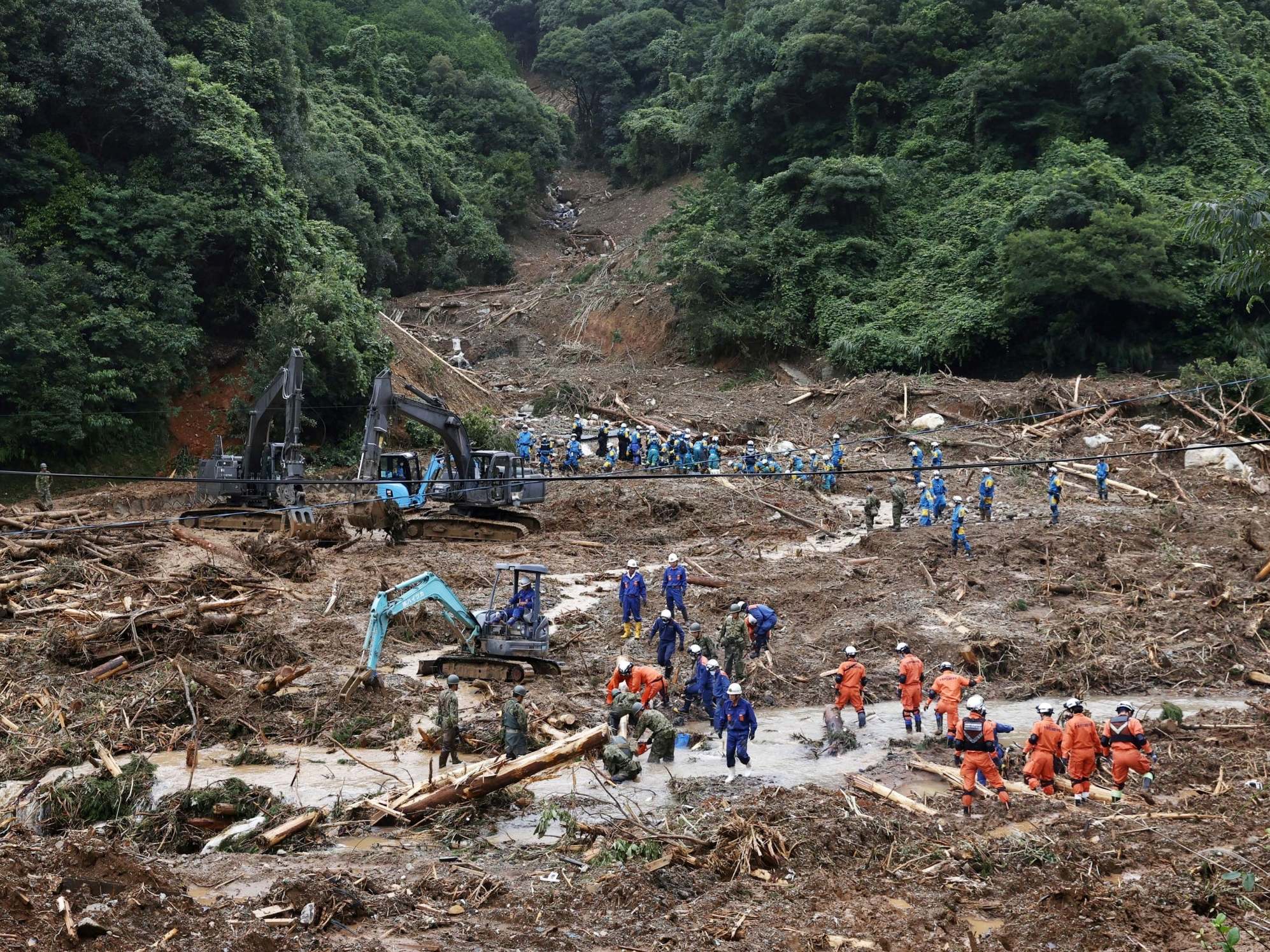 Rescue workers search for missing people at a landslide site caused by torrential rain in Tsunagi Town on the island of Kyushu