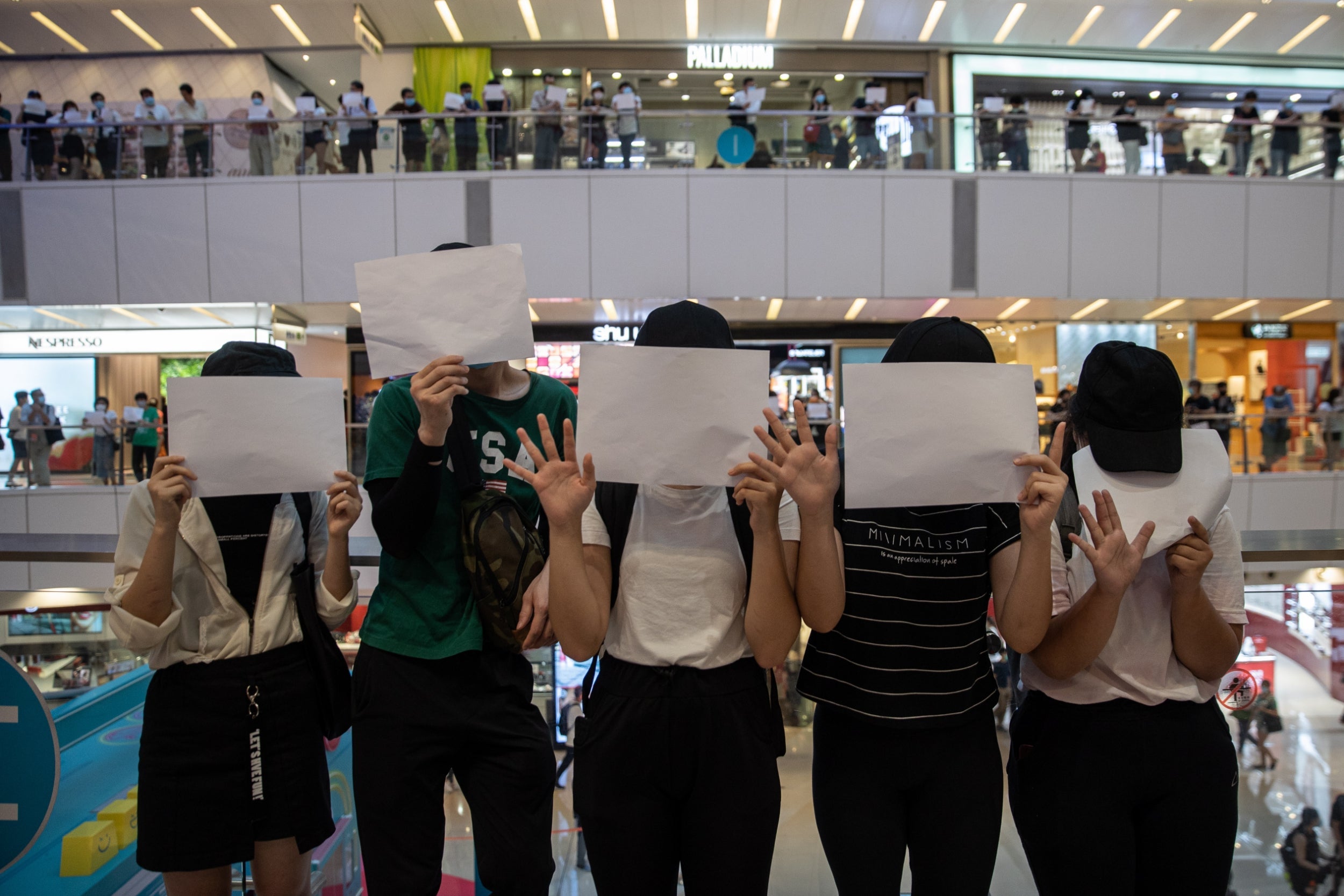 Protesters display blank sheets of white paper during a protest over freedom of speech in a shopping mall in Hong Kong on Monday