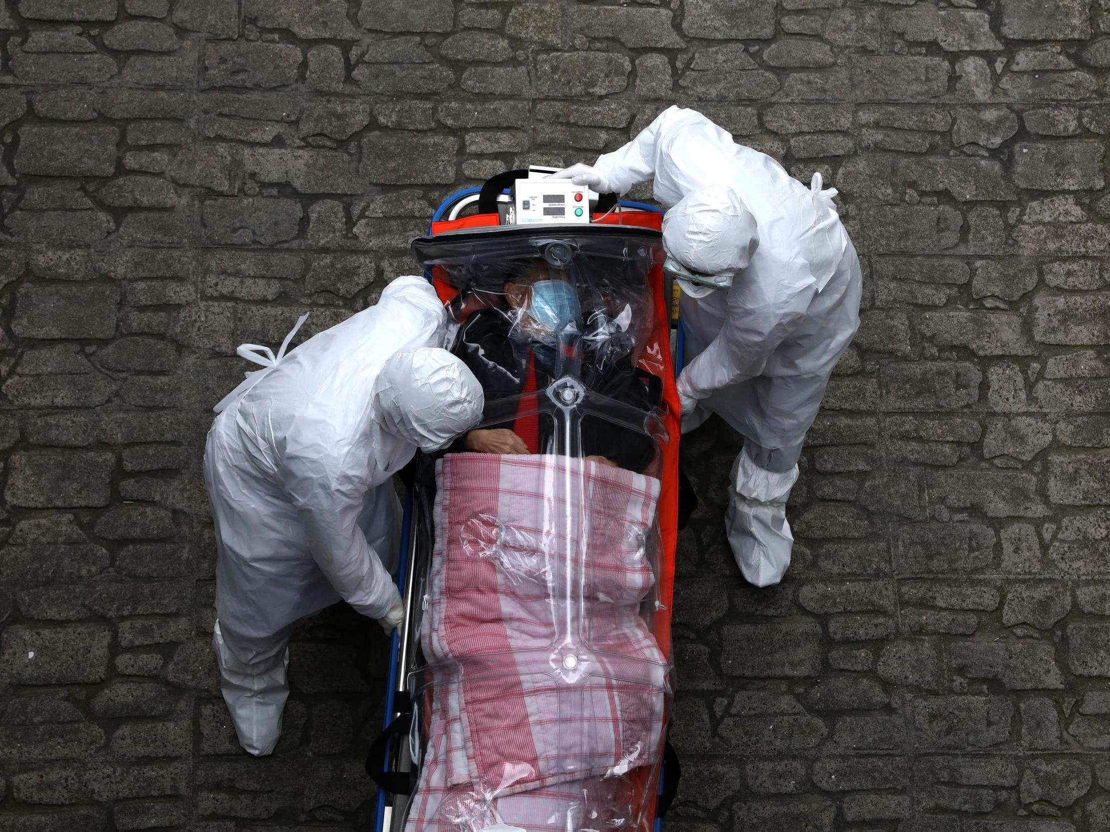 Healthcare workers move a patient infected with coronavirus from an ambulance to a hospital in Seoul