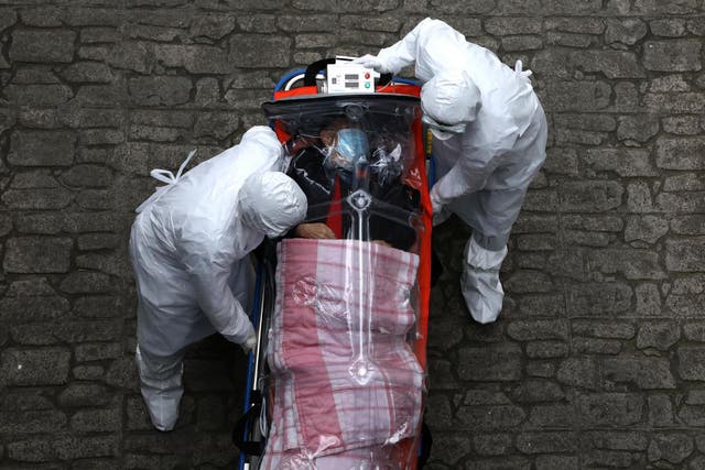 Healthcare workers move a patient infected with coronavirus from an ambulance to a hospital in Seoul