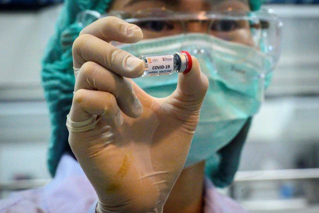 This picture taken on 23 May 2020 shows a laboratory technician holding a dose of a Covid-19 novel coronavirus vaccine candidate ready for trial in Thailand