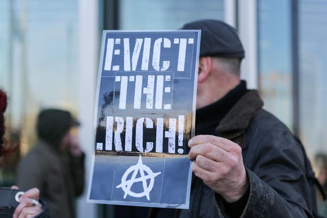 An anarchist holds aloft a placard at an anti-gentrification protest in London in 2018
