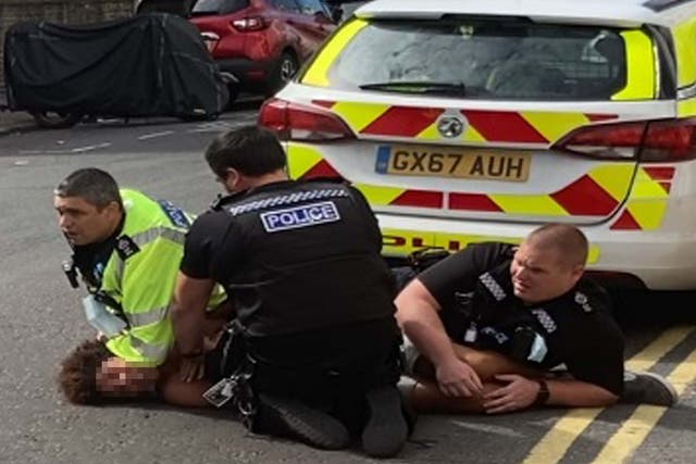 A man lies on the ground restrained by three Sussex Police officers in Brighton, 7 July 2020.