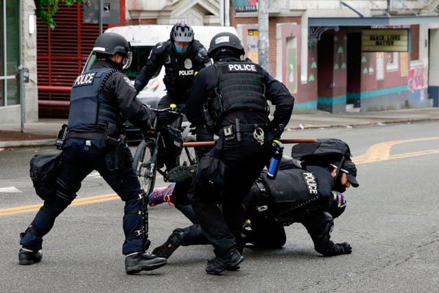 Police officers tackle a demonstrator to the floor at Seattle's CHOP zone, where Independent reporter Andrew Buncombe was arrested