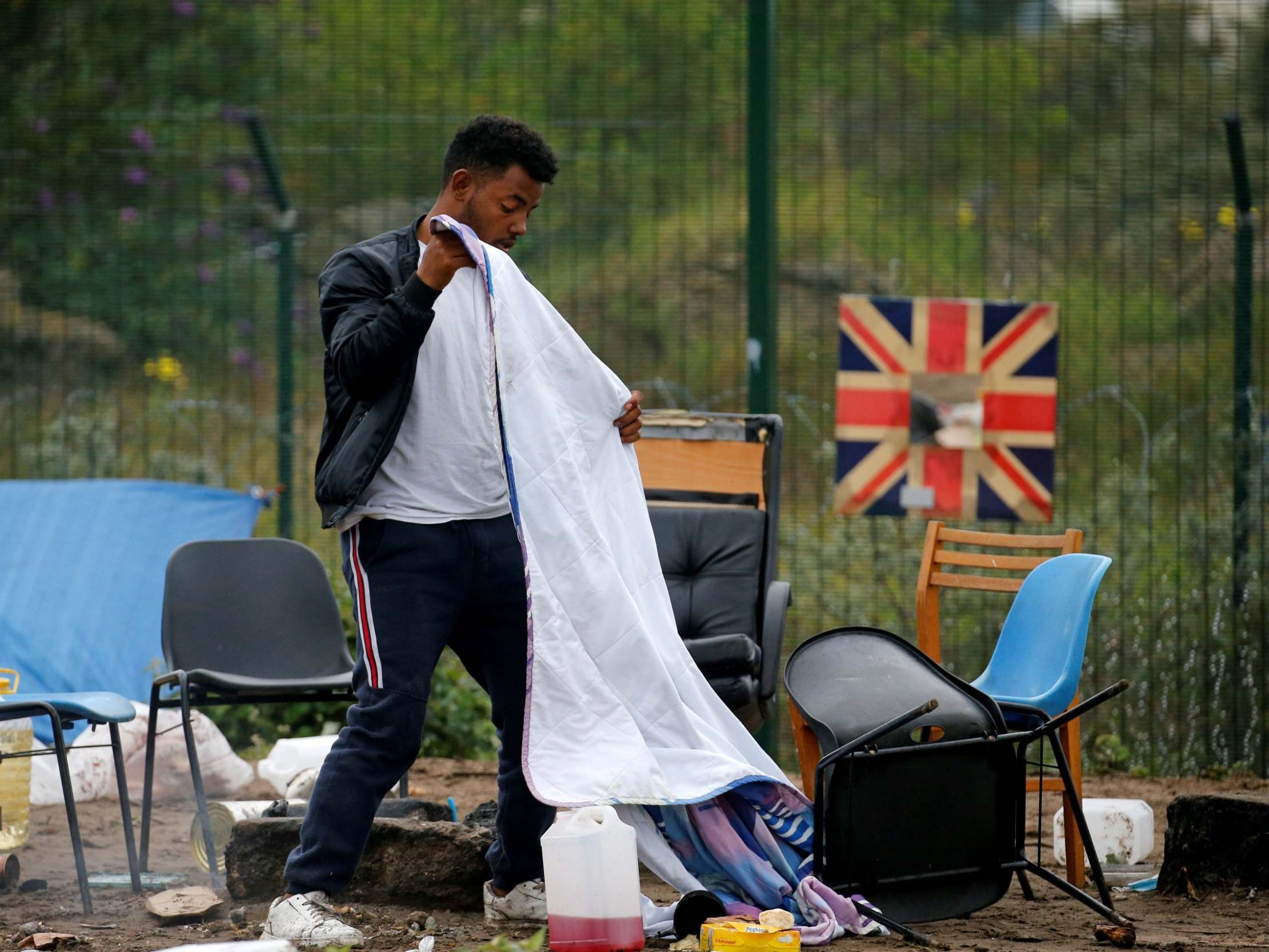 A man packs his belongings as police officers clear a refugee camp in Calais, France.