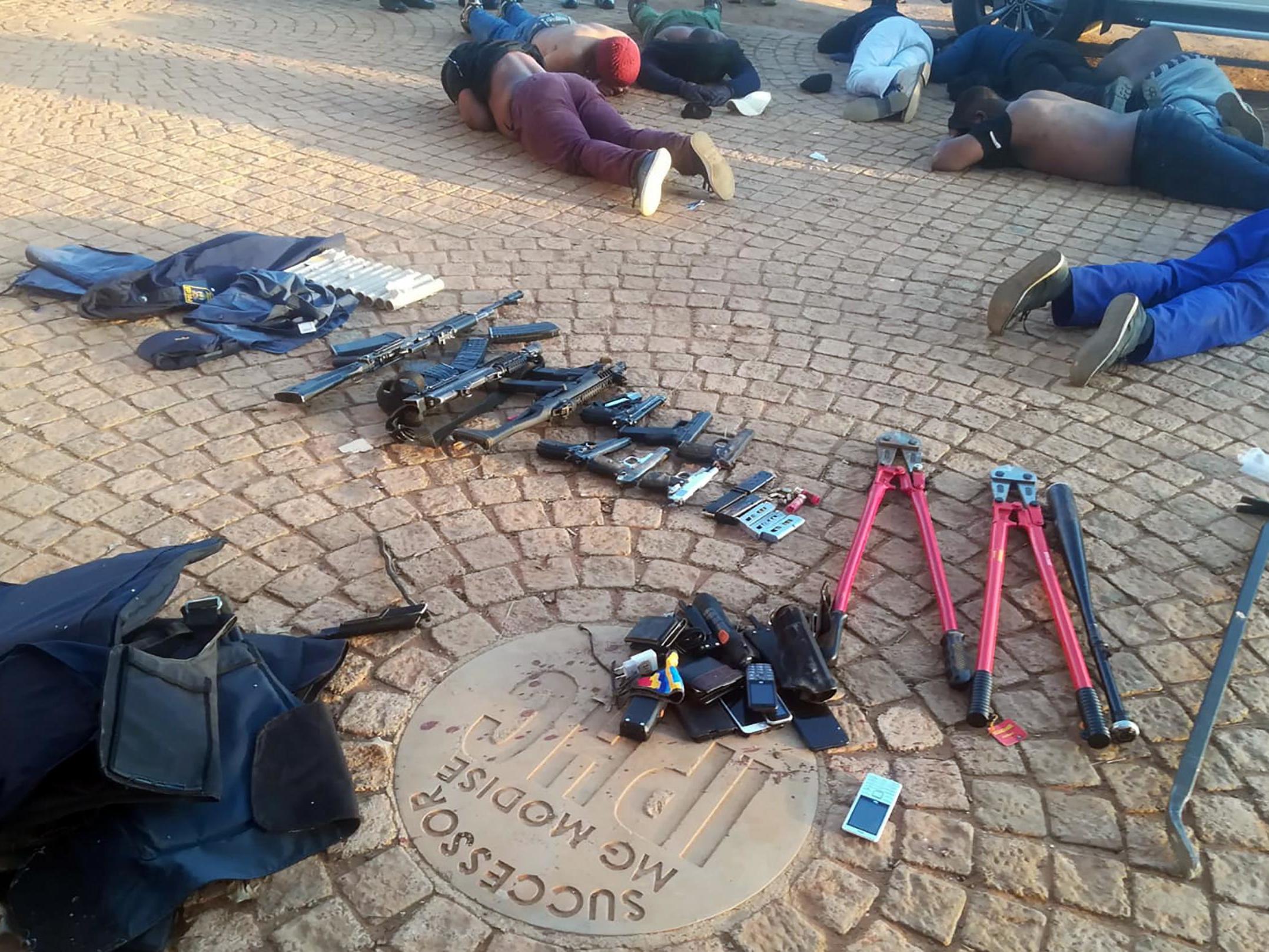 Arrested suspects and confiscated weapons are pictured at a church near Johannesburg after a siege on 11 July, 2020.