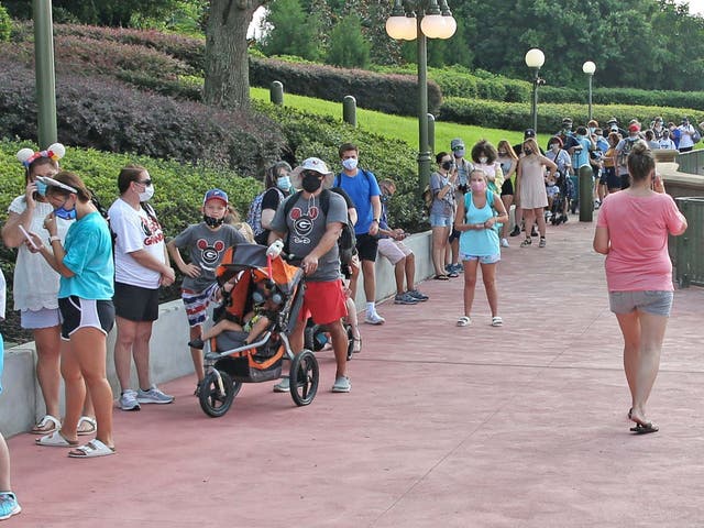 Guests wearing protective masks wait to pick up their tickets at the Magic Kingdom theme park at Walt Disney World on the first day of reopening, in Orlando, Florida, on July 11, 2020