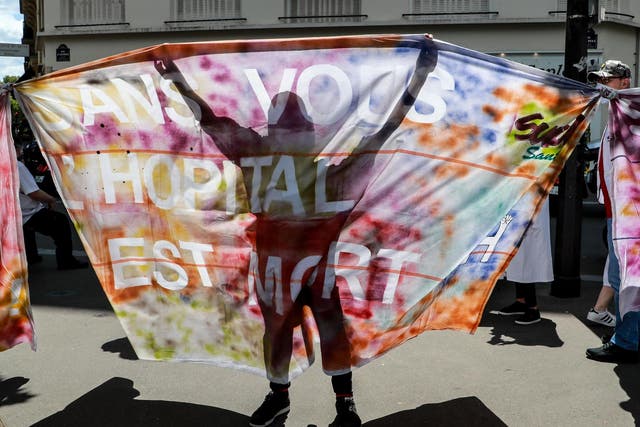 Health workers and trade unions representatives hold a banner reading 'without you, hospital is dead' during a demonstration next to the Health Ministry in Paris