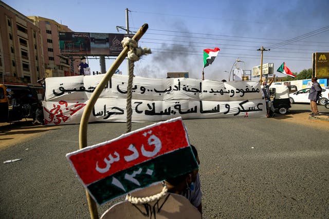 Sudanese protesters hold up canvas signs demanding in Arabic justice and accountability for a raid on an anti-government sit-in