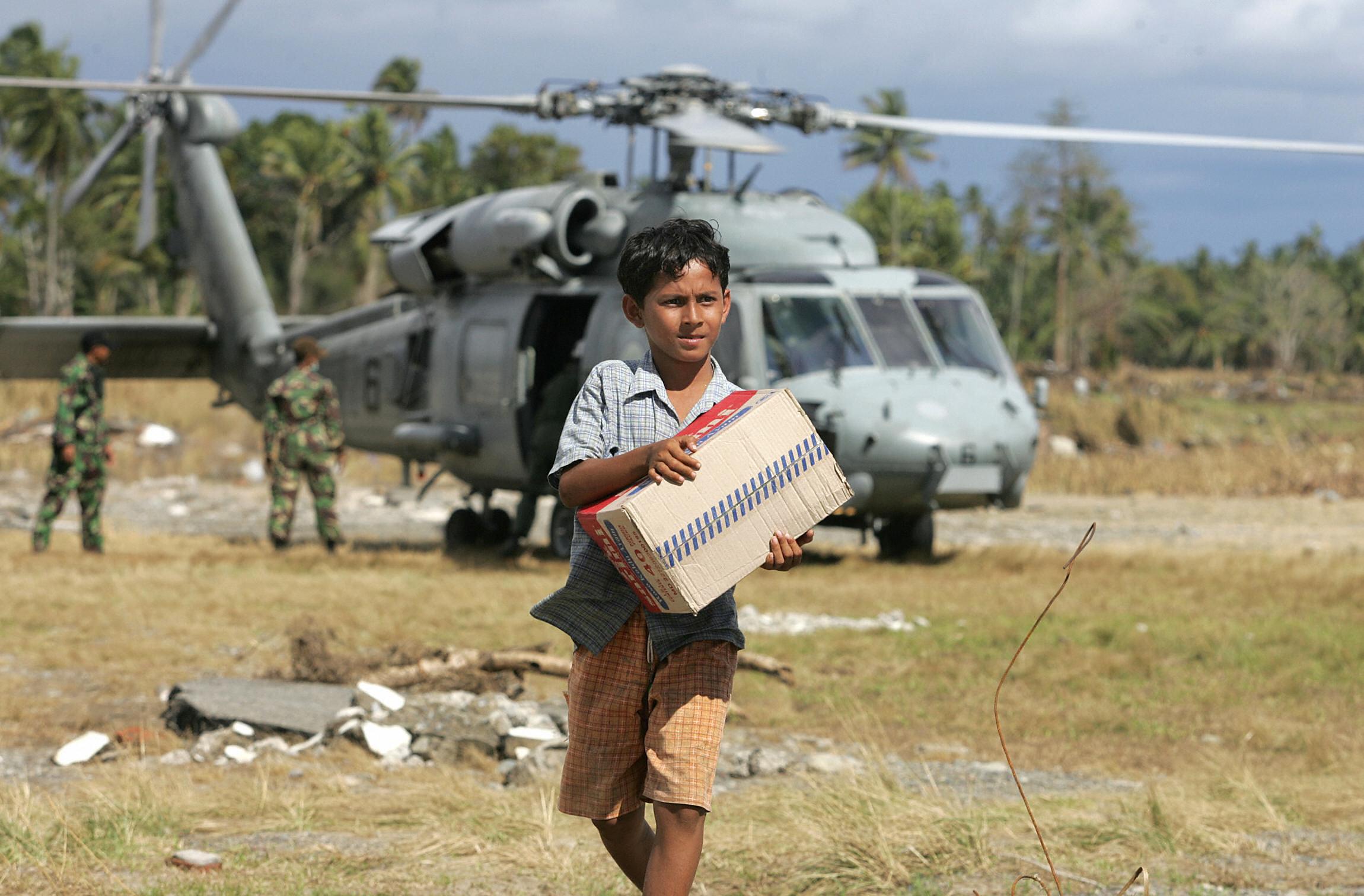 A boy collects supplies brought by a US Seahawk helicopter after the 2004 tsunami killed around 230,000 people and displaced millions more