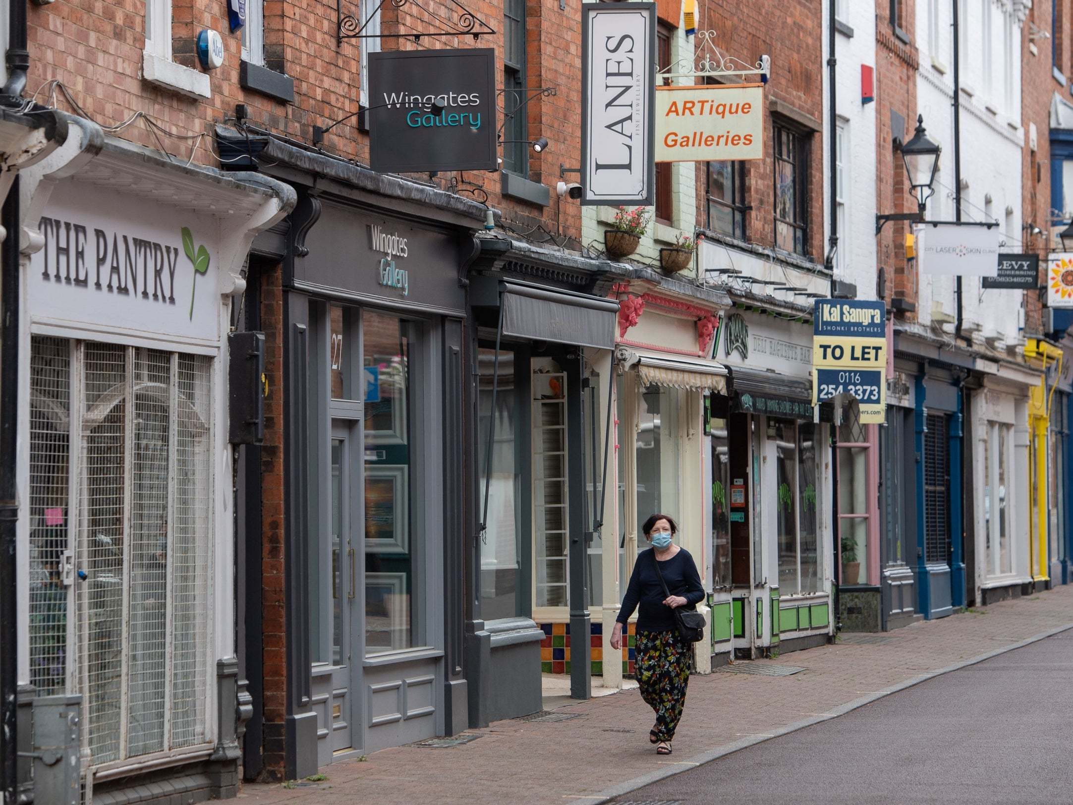 A woman wearing a face mask walks along a steeet of closed shop in Leicester where localised coronavirus lockdown restrictions have been in place since 29 June