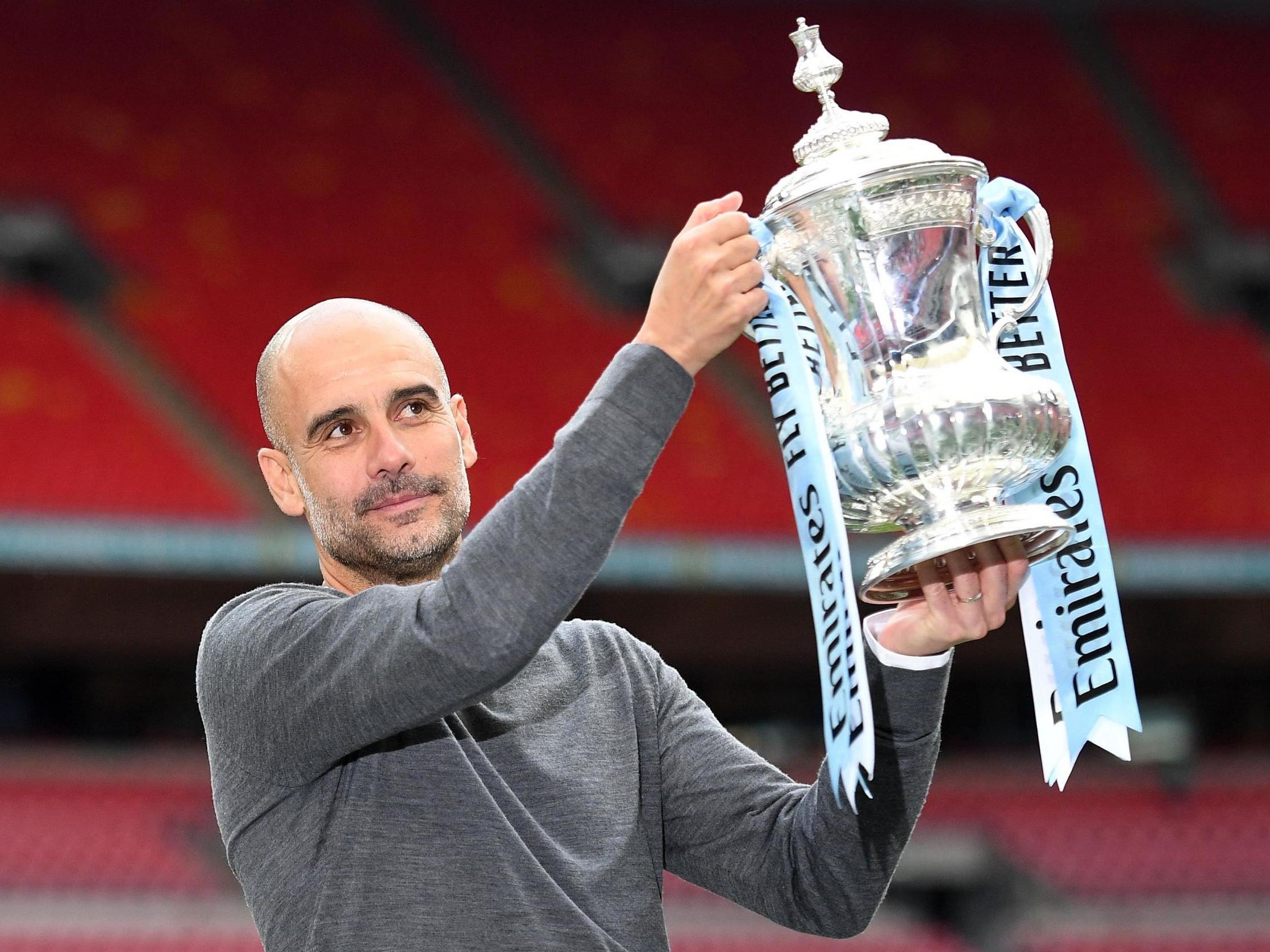 Manchester City manager Pep Guardiola raises the FA Cup trophy in 2019