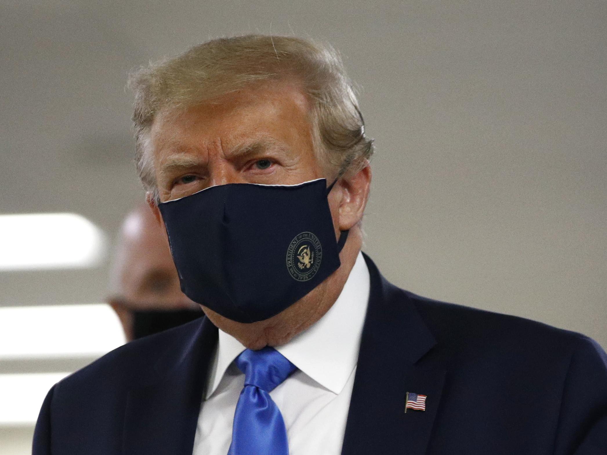 Donald Trump wears a face mask publicly for the first time, as he walks down a hallway during a visit to Walter Reed National Military Medical Centre in Bethesda